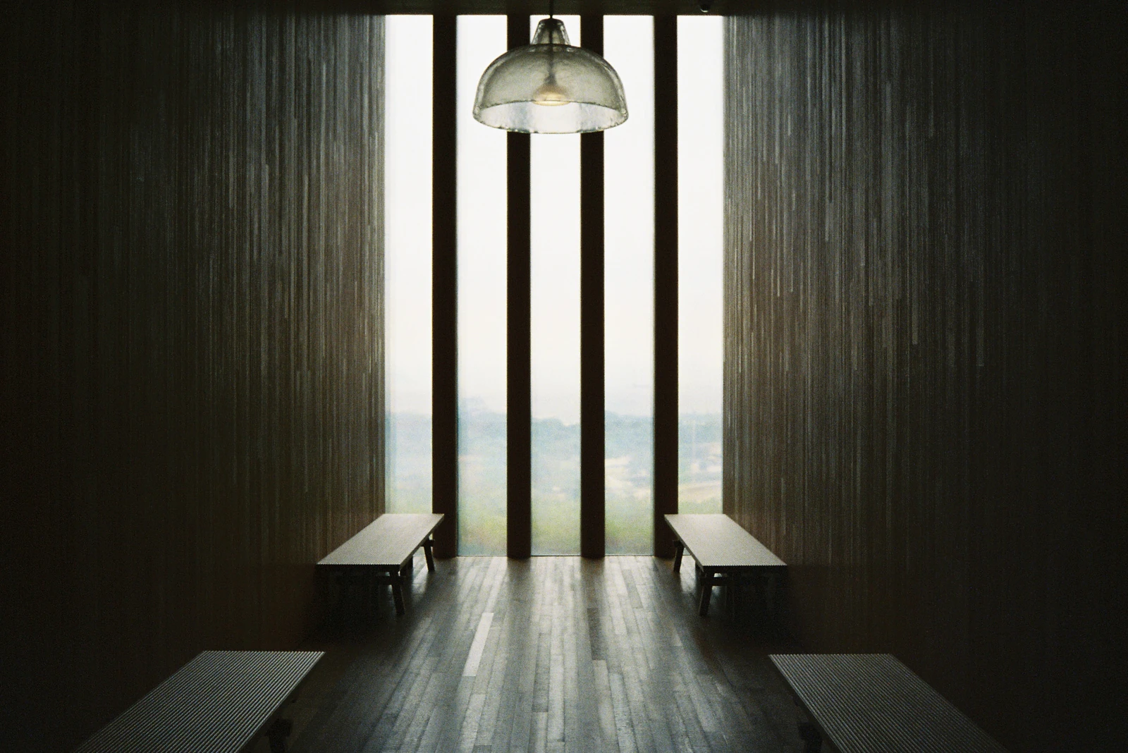 Benches beneath tall slit windows and a glass pendant light inside M+ in West Kowloon